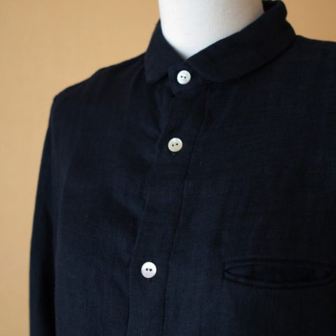 少し光沢があるリネン生地を二重にしたシャツになります。 コンパクトな襟元のデザインと黒蝶貝のボタンがアクセントになっています。